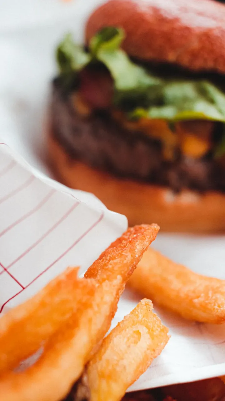 Hamburguesa con papas servida sobre papel, Brasa & Humo, San José